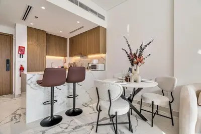 a kitchen and dining room with a table and chairs at Elegant 1-Bed with Pool, Gym, Parking and Balcony in Dubai