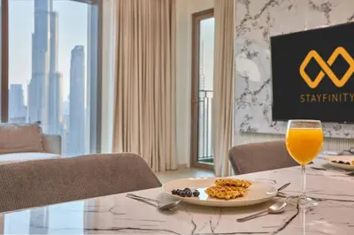 a table with a plate of food and a glass of orange juice at Luxury 4 Bedroom High-Floor Apartment, Spectacular Burj Khalifa & Fountain Views, Steps Away from Dubai Mall - Downtown Dubai by Stayfinity in Dubai