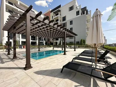 a pool with chairs and umbrellas in front of a building at Chic 1BR on La Mer Upgraded & Elegant in Dubai