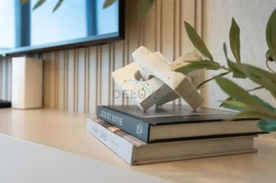 a stack of books sitting on a table with a plant at 2BR with Balcony Overlooking City and Burj Khalifa, Minutes Away from Dubai Mall, Paramount Tower Hotel and Residences, Business Bay by Deluxe Holiday Homes in Dubai