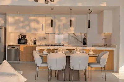 a kitchen with a table and chairs in a kitchen at La Vie Jumeirah Beach Residence 3 Bedroom Beachfront Apartment with Palm Views in Dubai
