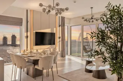 a dining room with a table and chairs and a television at La Vie Jumeirah Beach Residence 3 Bedroom Beachfront Apartment with Palm Views in Dubai