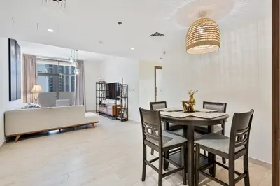 a dining room and living room with a table and chairs at Modern 2BR with Private Terrace, Pool and Gym Access in Dubai