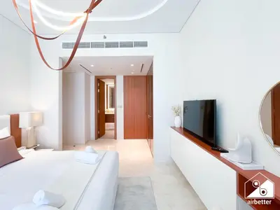 a white room with a bed and a tv at High End 1BR Palm Beachfront Pool Access in Dubai