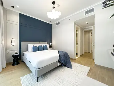 a bedroom with a bed and a blue accent wall at Elegant 2BR Plus Guest Room Stay with Designer Interior in Dubai