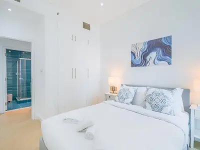 a white bedroom with a white bed and a painting at TRPS - Marina Heights Tower, Dubai Marina - 2BR Upgraded Apartment - with Stunning Marina Skyline in Dubai