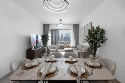 a dining room with a table with chairs and a couch at 2 Bedroom Apartment BLVD Central 1 with Boulevard Views in Dubai