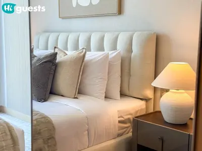 a bed with pillows and a lamp on a table at HiGuests - Wake up to Burj Khalifa views in stunning 2 BR in Dubai