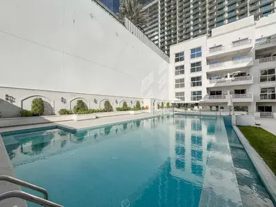 a large swimming pool in front of a building at Stylish JVC 2BR Stay with Guest Room Rose Gold Accents in Dubai