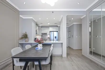 a kitchen and dining room with a table and chairs at Stylish JVC 2BR Stay with Guest Room Rose Gold Accents in Dubai