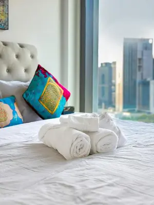 a pile of towels on a bed with a window at Downtown Views II 2 Bedroom Apartment Next to Dubai Mall in Dubai