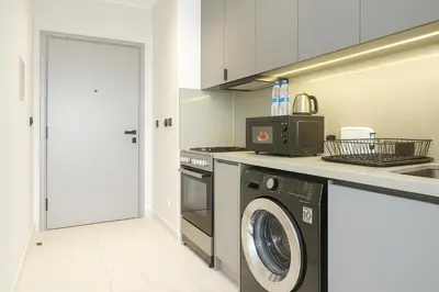 a kitchen with a washing machine and a microwave at Stylish Studio in Meydan 10mins away Burj Khalifa in Dubai