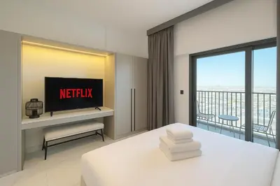 a bedroom with a bed and a tv and a balcony at Stylish Studio in Meydan 10mins away Burj Khalifa in Dubai