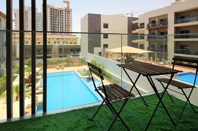 a balcony with a table and chairs and a swimming pool at Contemporary JVC Studio with Rooftop Pool Gym in Dubai