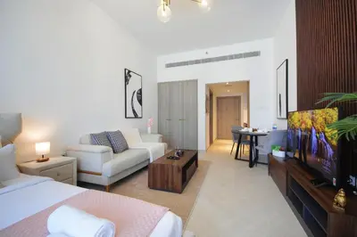 a room with a bed and a living room with a tv at Contemporary JVC Studio with Rooftop Pool Gym in Dubai