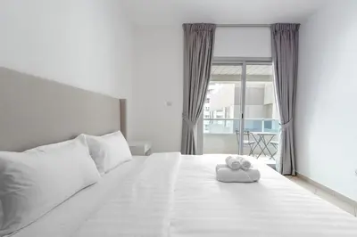 a white bed with a teddy bear sitting on it at Apartment Close to Metro in Dubai Marina in Dubai