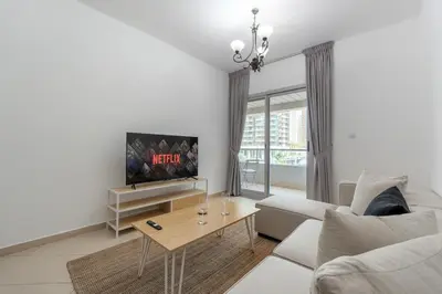 a white living room with a tv and a couch at Apartment Close to Metro in Dubai Marina in Dubai