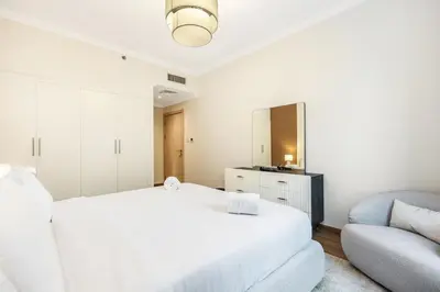 a white bedroom with a bed and a chair at Luxury 1BR Dubai Marina Apartment Walk to JBR Beach & Marina Yacht Club in Dubai