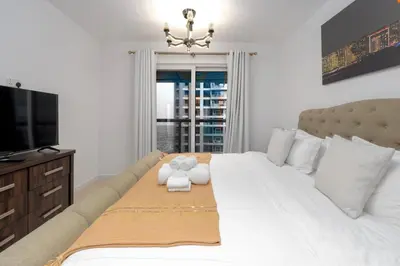 a bedroom with a large white bed with a television at Duplex Penthouse on 73rd Floor in Dubai Marina in Dubai