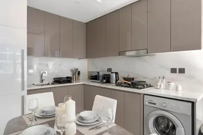 a kitchen with a table and a washing machine at Stylish 1BR near Business Bay, Meydan Racecourse & Crystal Lagoon in Dubai