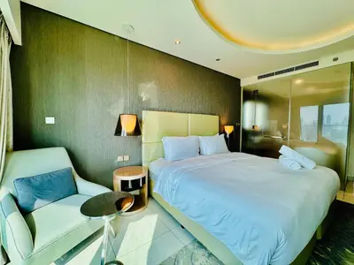 a bedroom with a large bed and a chair at Luxe 3BR , Paramount by DAMAC, Excellent Pool in Dubai