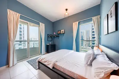 a blue bedroom with a bed and large windows at Best View in Marina Dubai in Dubai