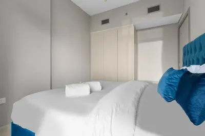 a bedroom with a large white bed with blue pillows at FIRST CLASS 1BR Contemporary Comfort in Dubai