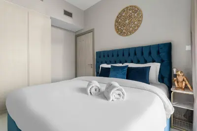 a bedroom with a large white bed with towels on it at FIRST CLASS 1BR Contemporary Comfort in Dubai
