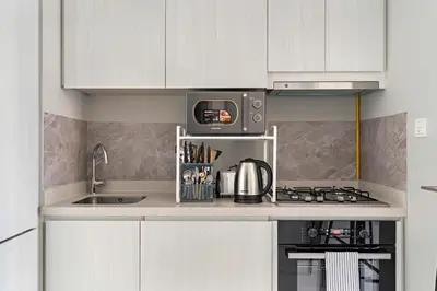 a kitchen with white cabinets and a stove and a microwave at FIRST CLASS 1BR Contemporary Comfort in Dubai