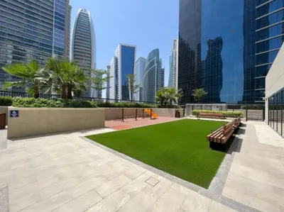 a park with benches and grass in a city at FIRST CLASS 1BR Contemporary Comfort in Dubai
