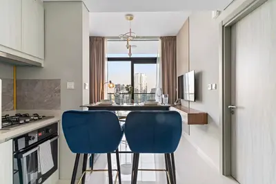 a kitchen with two blue chairs at a kitchen island at FIRST CLASS 1BR Contemporary Comfort in Dubai