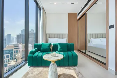 a living room with a green couch and a bed at Charming Studio with Scenic Canal Views in Dubai
