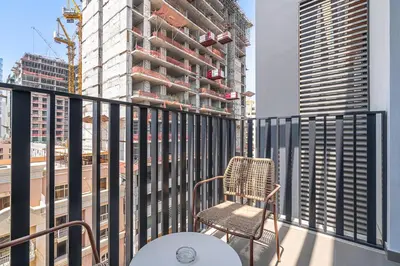 a chair on a balcony with a building under construction at Bright Studio in JVC with Pool and Gym Access in Dubai