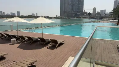 a swimming pool with chairs and umbrellas on a building at Highend Azure 1BR Sea View and Private Beach with Pool Access in Dubai