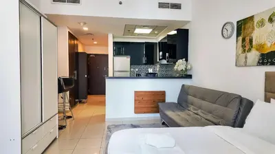 a living room with a couch and a kitchen at Silk Valley - Cozy Studio steps away from the Beach and Marina in Dubai