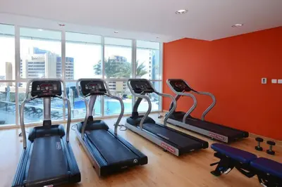 a gym with three elliptical exercise bikes in a room at Silk Valley - Cozy Studio steps away from the Beach and Marina in Dubai