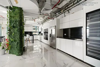 a kitchen with white cabinets and a green wall at Luxe 3-Bedroom Sky Retreat in Dubai Marina in Dubai