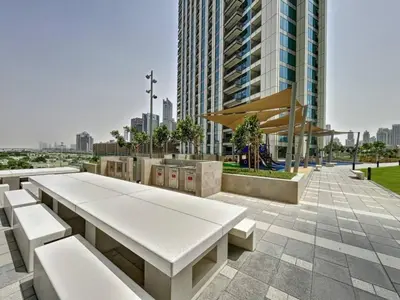 a park with white benches and a tall building at FIRST CLASS 1BR Stylish Gem Near Dubai Mall in Dubai