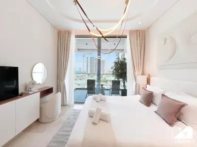 a white bedroom with a large bed and a tv at Seafront Serenity Palm Escape with Pool Access in Dubai