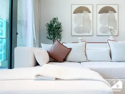 a living room with a white couch with pillows at Seafront Serenity Palm Escape with Pool Access in Dubai