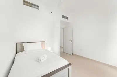 a white bedroom with a bed with white sheets at FIRST CLASS 2BR Cozy City Retreat in Dubai