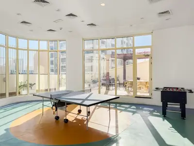 a ping pong table in a room with a pool at FIRST CLASS 2BR Cozy City Retreat in Dubai