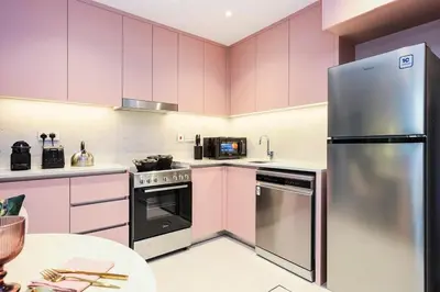 a kitchen with pink cabinets and a stainless steel refrigerator at FIRST CLASS 1BR Classic Luxe Getaway in Dubai