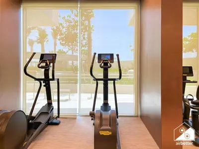 a gym with two tread machines in front of a window at Luxury Beachfront 1BR on Palm Jumeirah & Balcony in Dubai