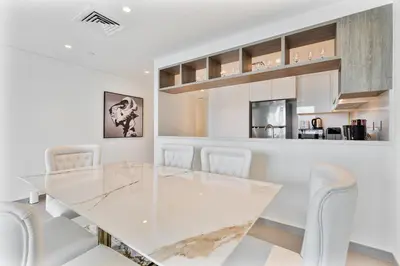 a white dining room with a glass table and chairs at 3BR APT with Burj View from Balcony - Pool and Gym in Dubai