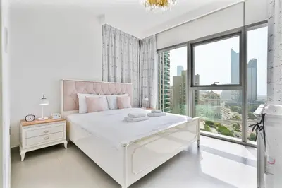 a white bedroom with a large bed and a window at 3BR APT with Burj View from Balcony - Pool and Gym in Dubai