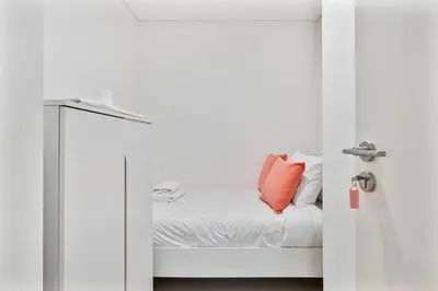 a white room with a bed with a red pillow at 3BR APT with Burj View from Balcony - Pool and Gym in Dubai