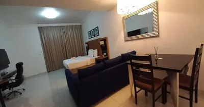 a living room with a couch and a table and a bed at Capital Bay city view Studio in Dubai