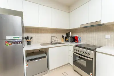a kitchen with white cabinets and a stainless steel refrigerator at On the dock Nice 1bedroom in Dubai Creek Harbour in Dubai