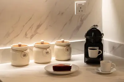 a table with three coffee pots and a plate of cake at Elegant 3-Bedroom Apartment - Panoramic Burj Khalifa and Downtown Views in Dubai